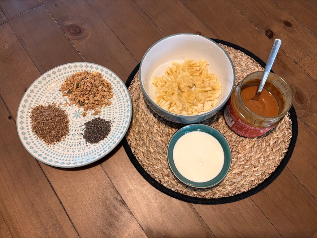Ingredients for breakfast nourish bowl with mashed banana, peanut butter, yoghurt, seeds and nuts