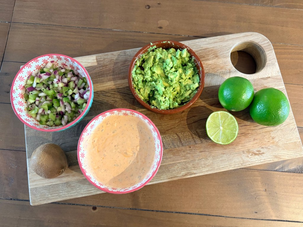 Bowls of salsa and limes on a wooden board